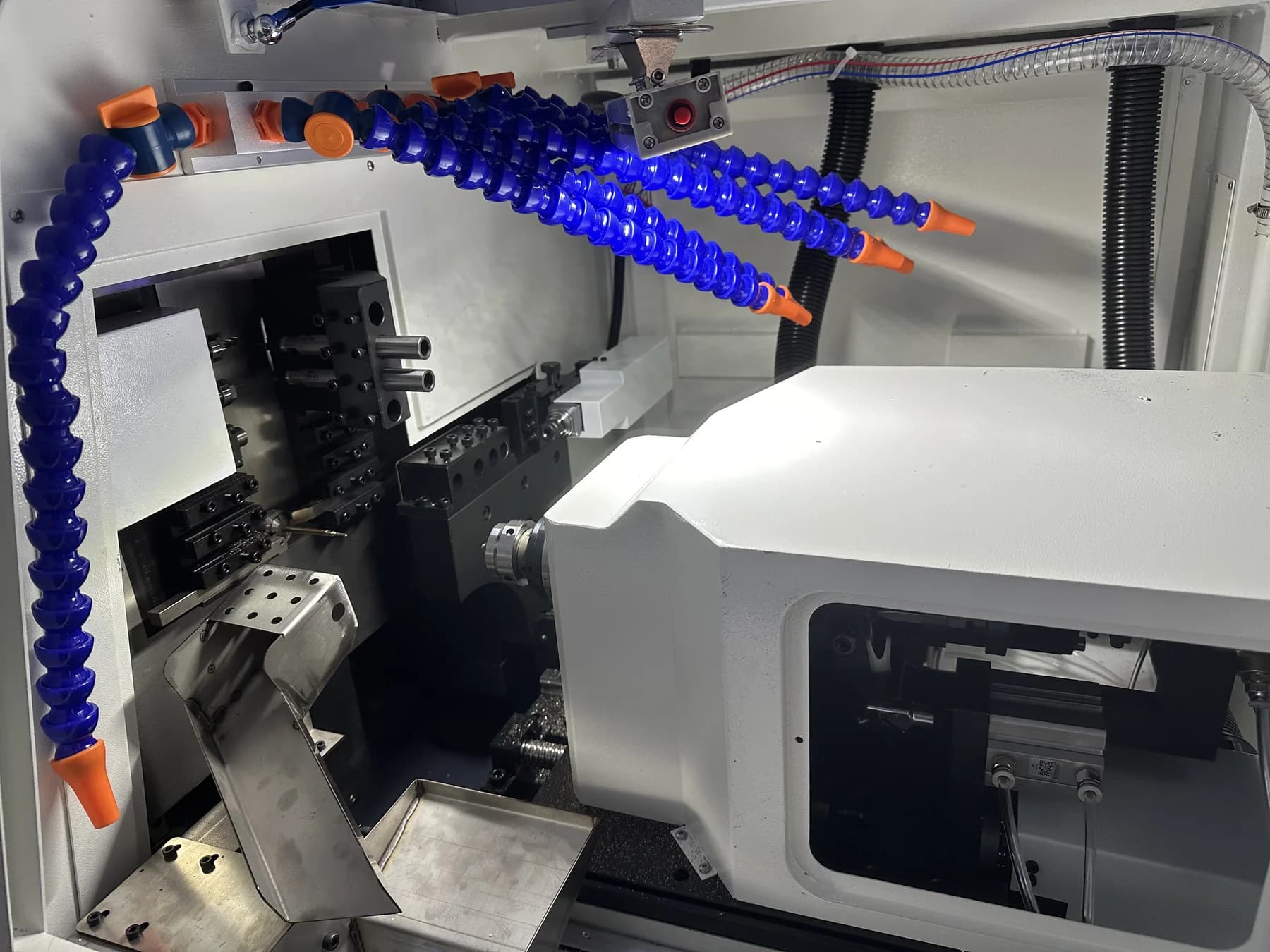 Swiss-type CNC lathe working area with tool positions and coolant lines visible